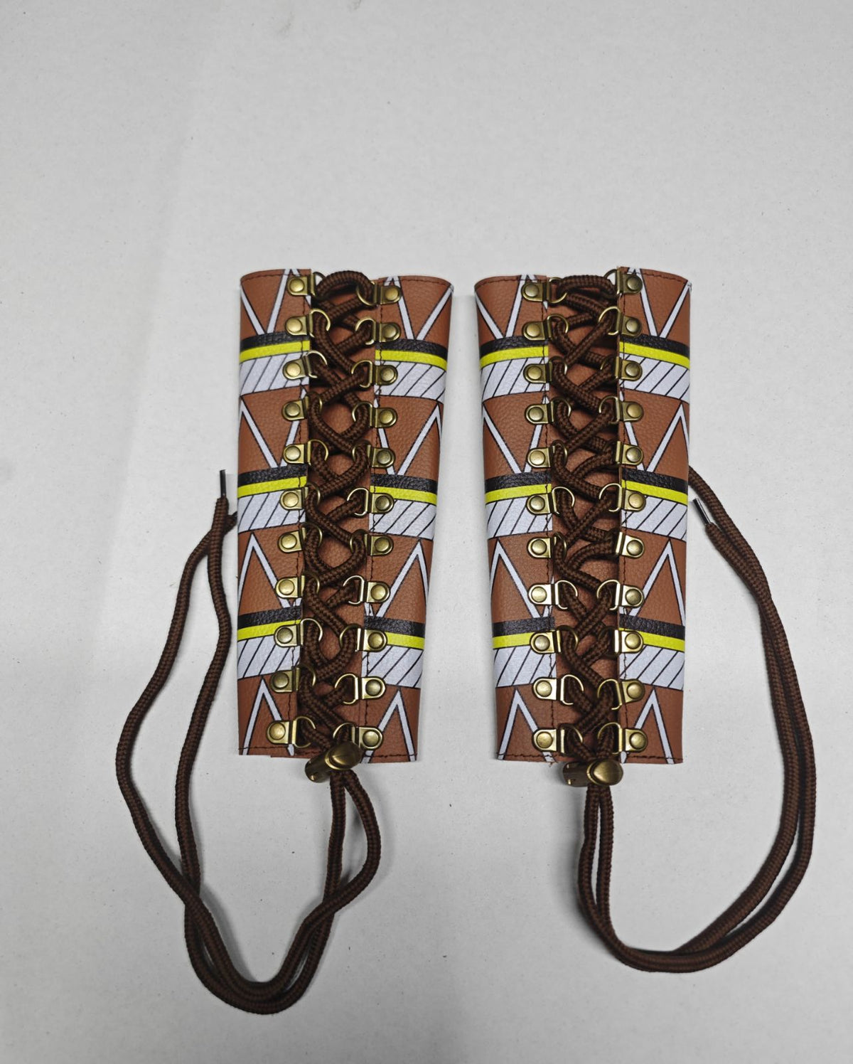 Two Earthsong brown leather arm cuffs with tribal print, brown lace-up cords and gold-tone metal loops.